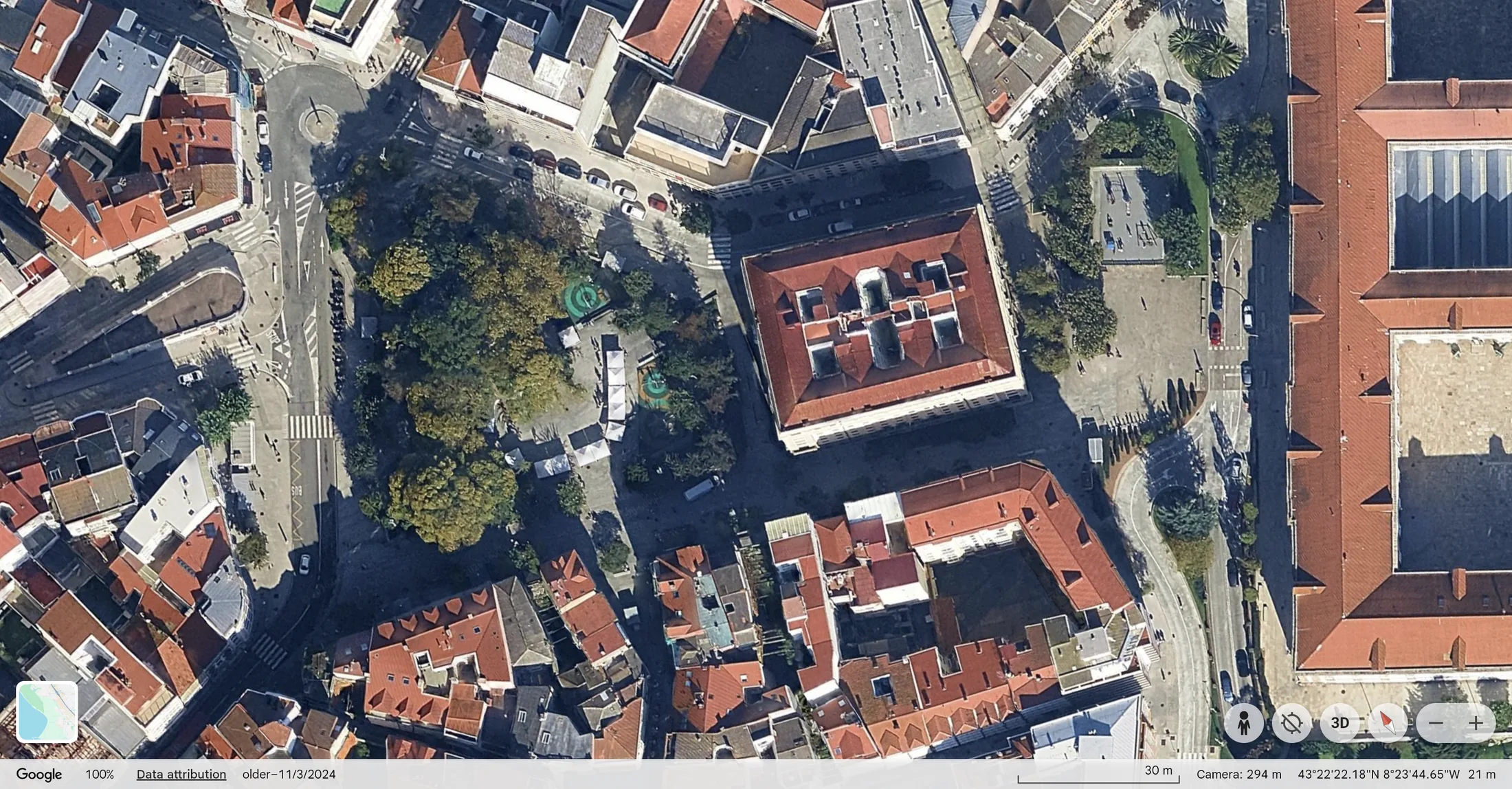 Praza de España, vista histórica de 2024: un xardín axardinado cunha fonte xunto ao edificio.